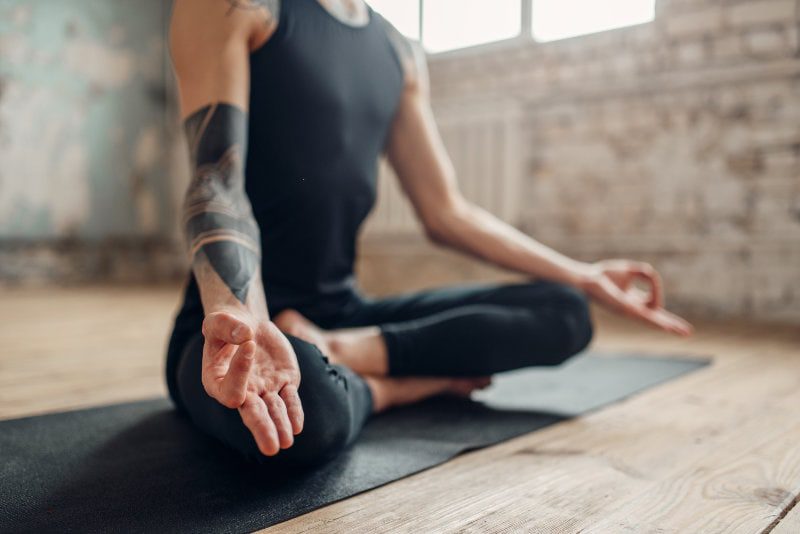 A person sitting on the ground doing yoga.