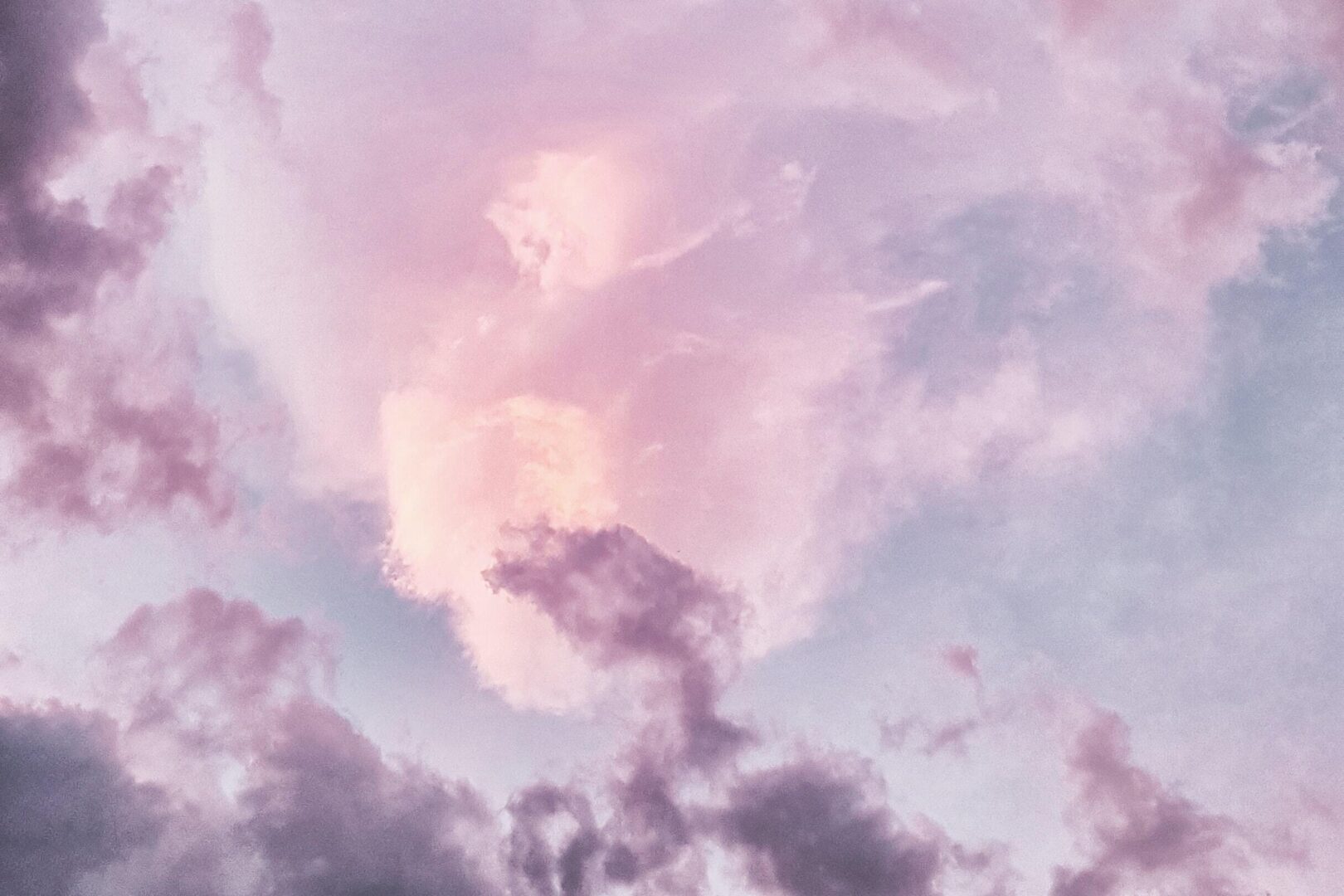 A pink cloud is in the sky with purple clouds.