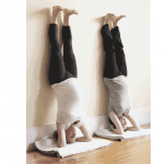 Two people doing a handstand on their hands.