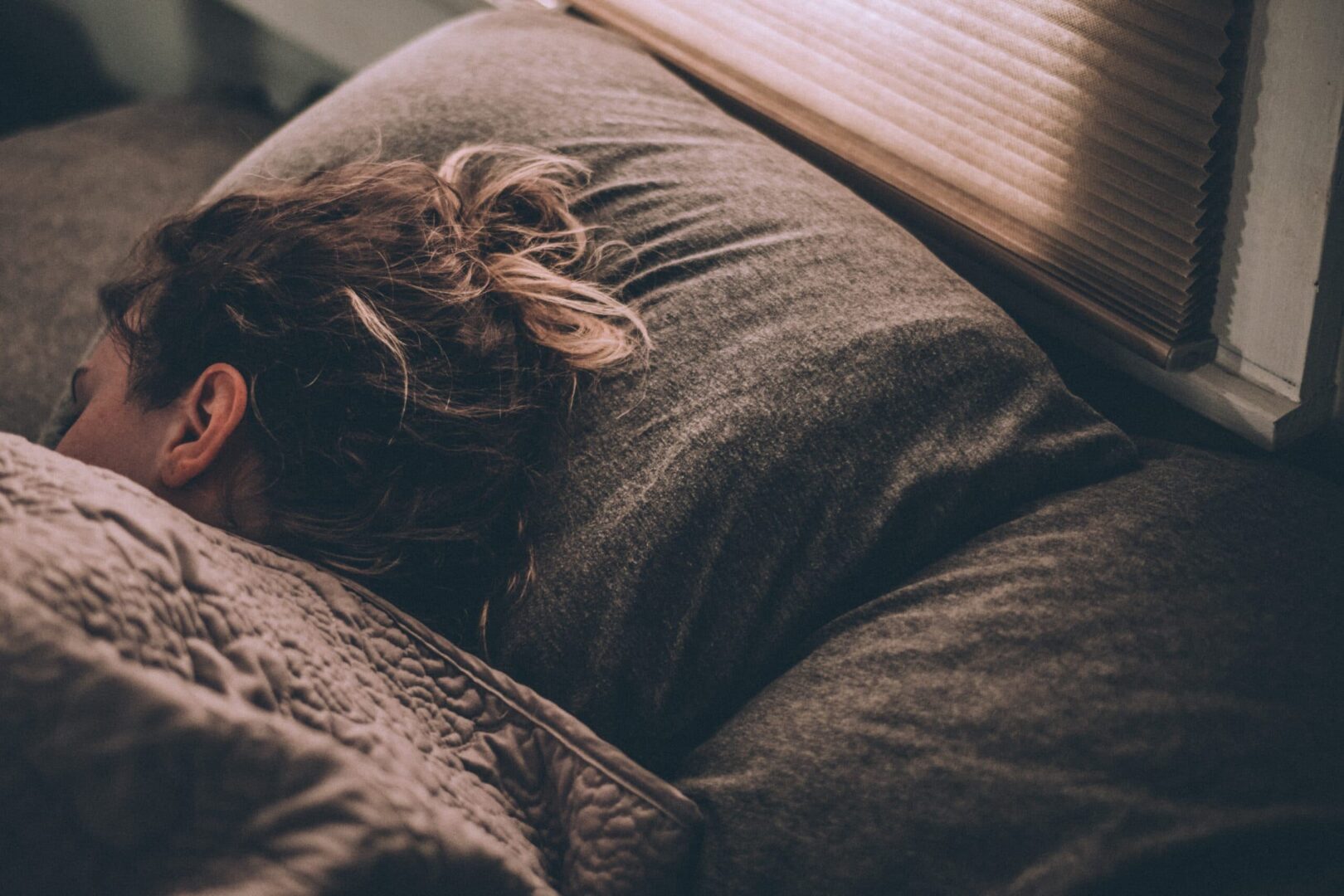 A person sleeping on the bed with their head down