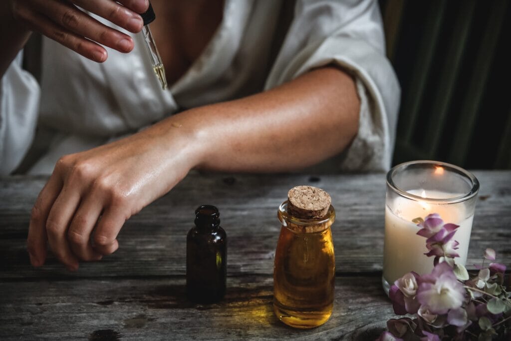 A person sitting at a table with some oils and a glass