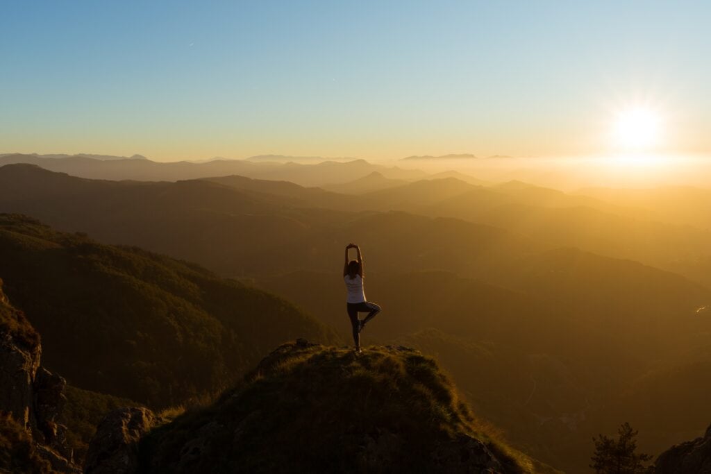 A person standing on top of a mountain doing yoga.