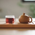 A cup of tea and teapot on a table.