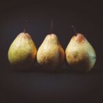 Three pears are sitting in a row on the table.