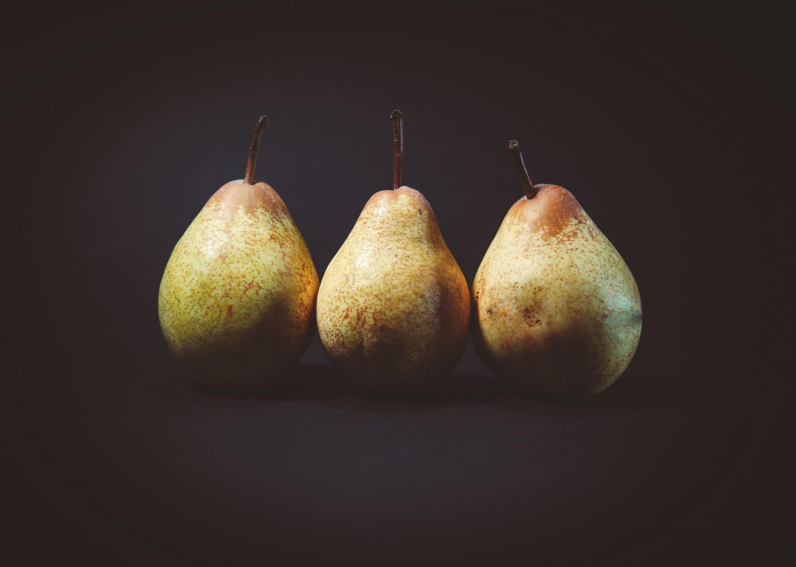 Three pears are sitting in a row on the table.