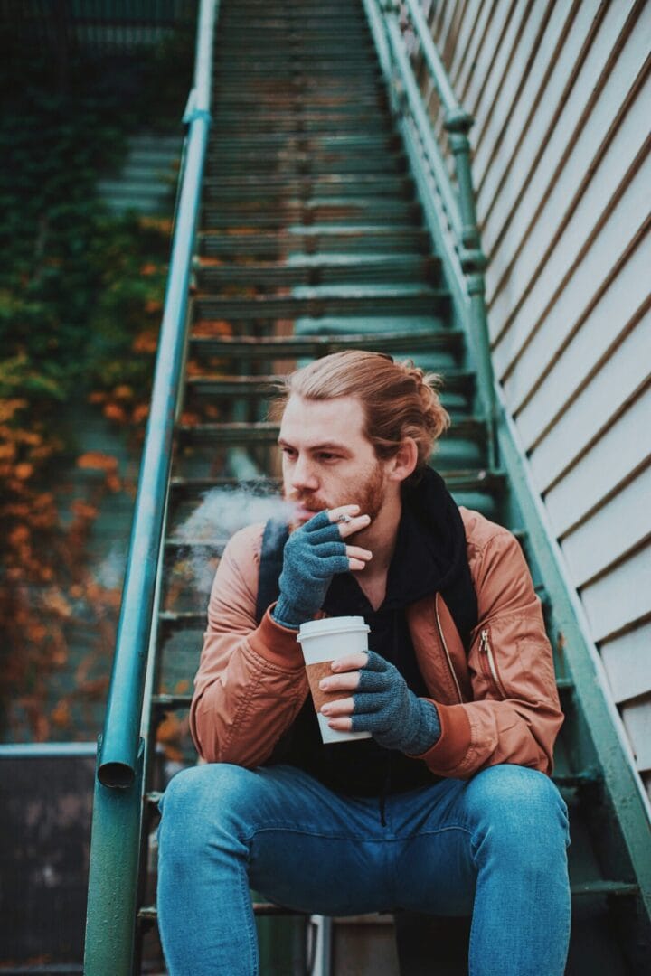 a man sitting on the stairs and smoking