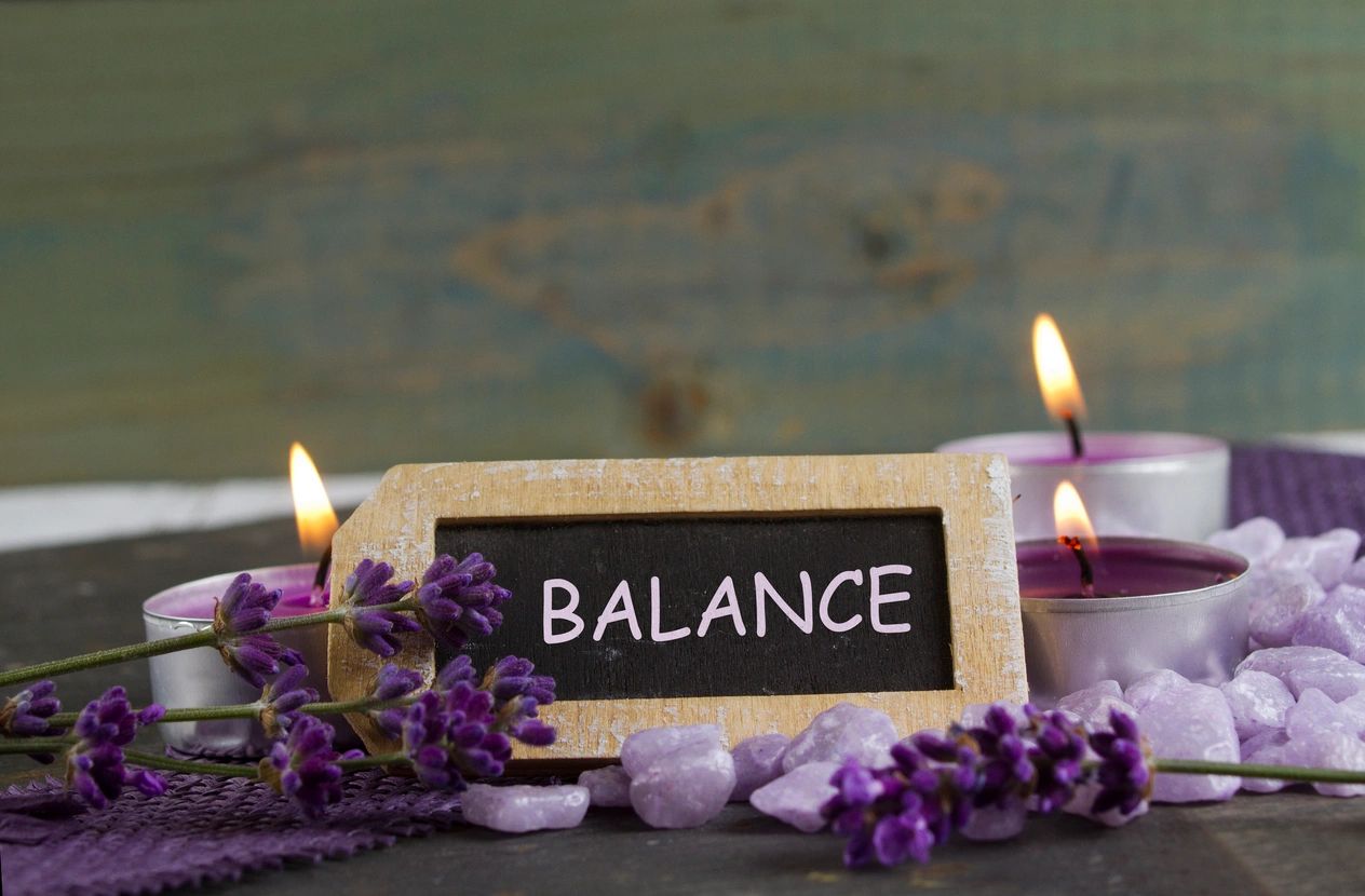Simple flowers on a table with a sign reading “Balance,” symbolizing Ayurvedic harmony of food, sleep, and energy.