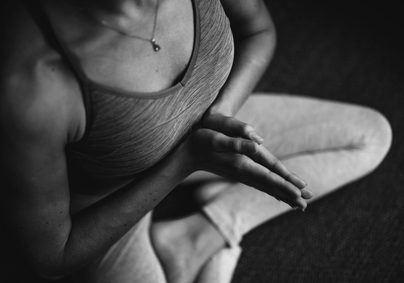 A woman sitting on the ground in a yoga pose.